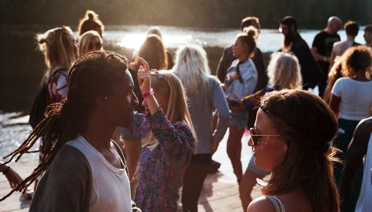 A group of students stand and dance near a body of water